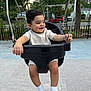 Sultan is registered to the contest to win money with this photo: toddler, child, swing, playground, outdoor, smiling, happy, socks, clothing, park, trees, metal_chains, seat, daylight, sidewalk, fence, residential_area, cute, joyful, person