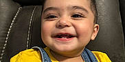 Sultan is registered to the contest to win money with this photo: baby, child, closeup, couch, cute, denim_overalls, expression, face, furniture, hair, happy, indoor, person, portrait, sitting, skin, smile, toddler, yellow_shirt, young_child