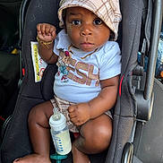 Milo is registered to the contest to win money with this photo: baby, bottle, bracelet, car_interior, car_seat, child, clothing, cute, face, foot, hand, hat, infant, milk, necklace, pacifier, person, plaid, seat_belt, wide_eyes