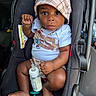 baby, infant, car_seat, bottle, milk, pacifier, hat, plaid, clothing, bracelet, necklace, child, person, seat_belt, car_interior, foot, hand, face, wide_eyes, cute