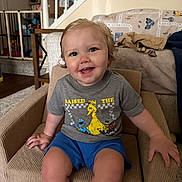 Beau joined the competition — help win amazing prizes! toddler, child, smiling, sitting, armchair, clothing, shorts, tshirt, indoor, living_room, furniture, staircase, blanket, happy, person, face, hair, carpet, home, cute