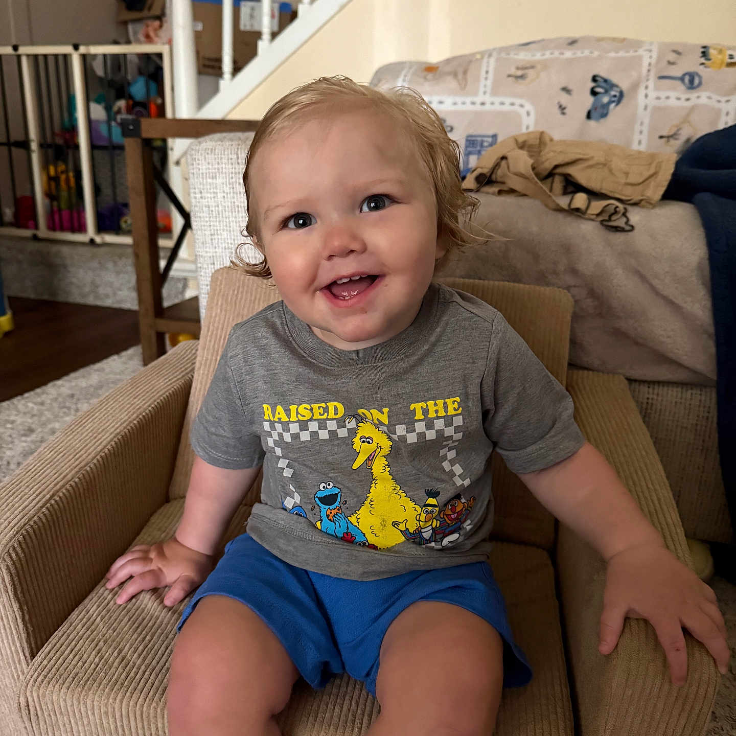 Beau joined the competition — help win amazing prizes! toddler, child, smiling, sitting, armchair, clothing, shorts, tshirt, indoor, living_room, furniture, staircase, blanket, happy, person, face, hair, carpet, home, cute