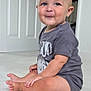 baby, child, sitting, carpet, indoors, tshirt, drool, smile, face, cute, young, person, skin, floor, room, door, short_hair, casual_clothing, expression, portrait