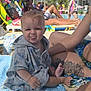 baby, child, poolside, sunny, towel, lounge_chair, tattoo, woman, hand, ring, sunglasses, umbrella, swimwear, outdoor, people, water, relaxation, summer, tongue_out, playful