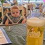 Jake is registered to the contest to win money with this photo: baby, background, beer, checkered, child, clothing, face, glass, green, high_chair, indoor, light, pacifier, people, person, plant, restaurant, seated, tablecloth, window