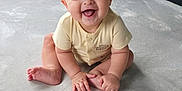 Jake is registered to the contest to win money with this photo: baby, carpet, child, clothing, cute, face, floor, furniture, hand, happy, indoor, infant, modern, person, short_sleeve, sitting, skin, smiling, toe, young
