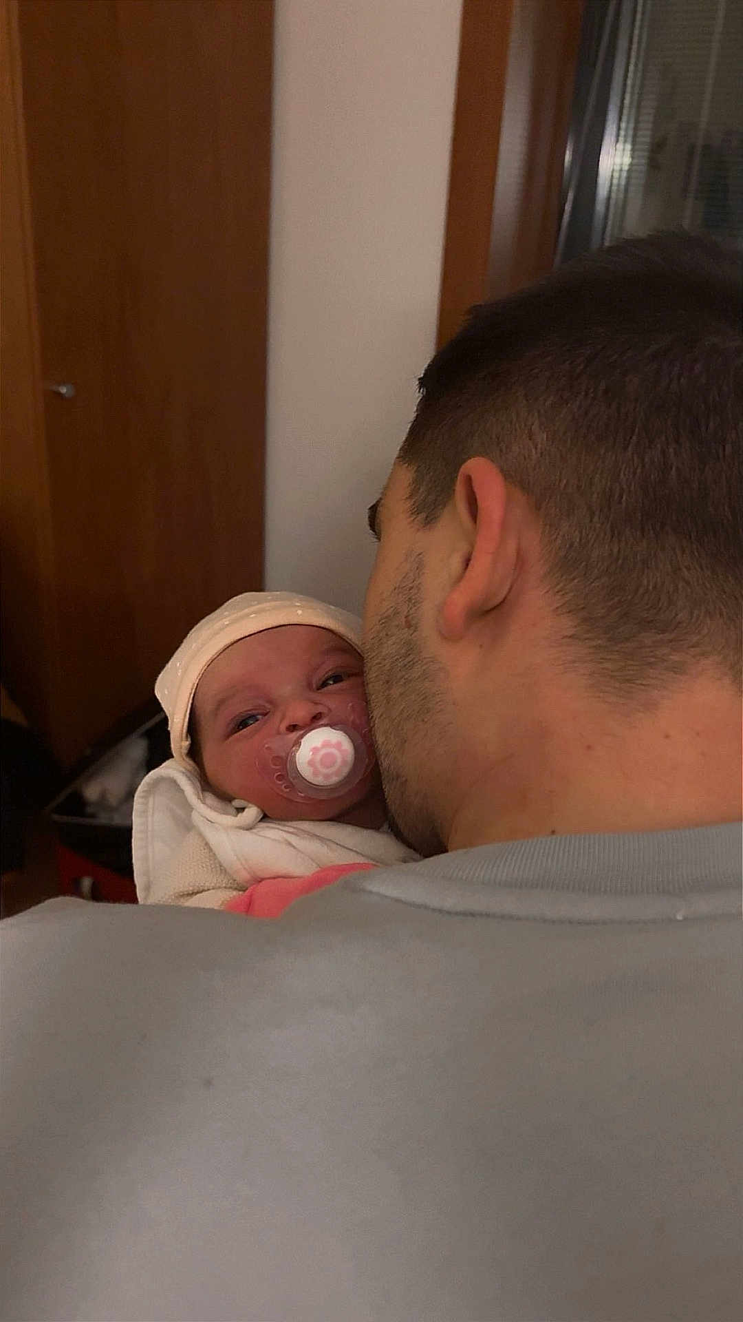 Lyana a rejoint le concours — aidez-le/la à gagner de superbes lots ! adult, baby, back_of_head, blanket, close_up, clothing, ear, furniture, hat, holding, indoor, man, newborn, pacifier, parenting, portrait, stubble, swaddle, warm_lighting, wooden_door