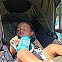 toddler, sleeping, stroller, child, baby, sippy_cup, outdoor, sunlight, foot, hand, seatbelt, canopy, summer, relaxation, nap, skin, toy, infant, daytime, shade