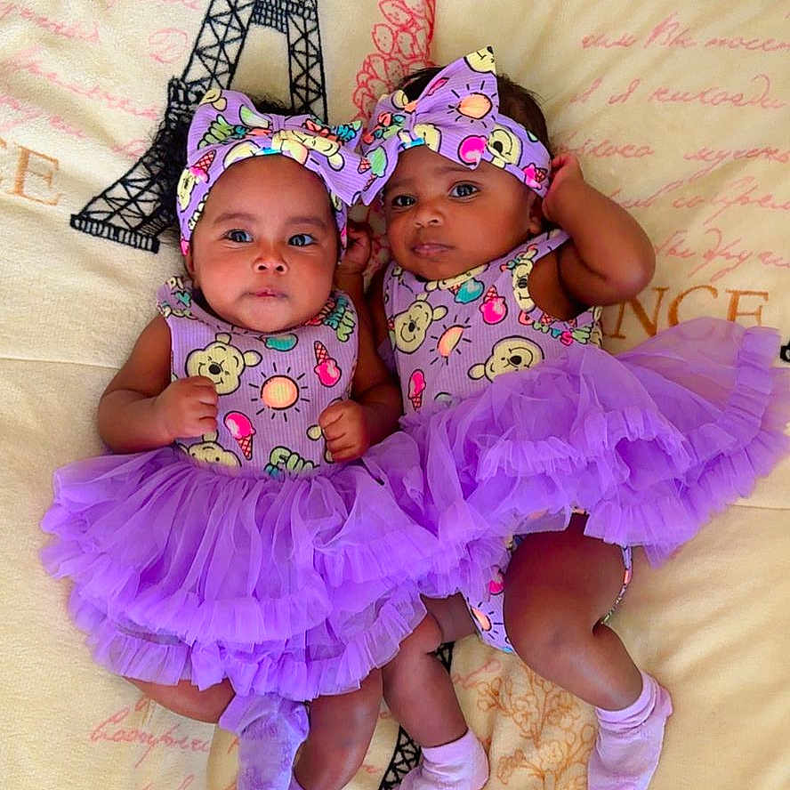 Ainara Y Aitana is registered to the contest to win money with this photo: adorable, baby, blanket, child, colorful, cute, eiffel_tower, fashion, headband, indoor, infant, lying_down, matching_outfits, playful, portrait, purple, smiling, socks, tutu, twins