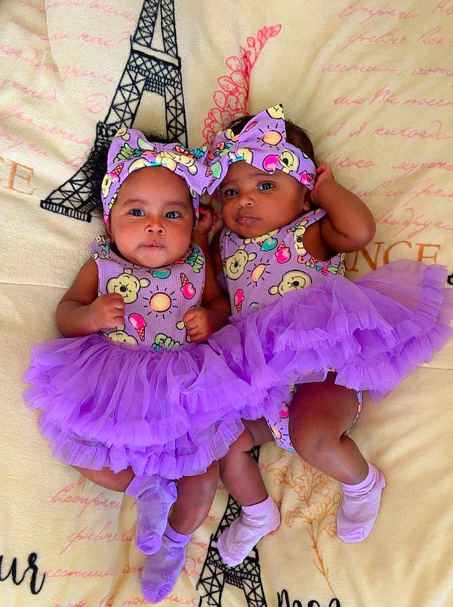 Ainara Y Aitana is registered to the contest to win money with this photo: baby, twins, tutu, purple, headband, infant, blanket, eiffel_tower, cute, smiling, lying_down, matching_outfits, socks, adorable, child, portrait, indoor, colorful, playful, fashion