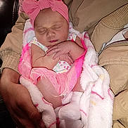 Alayia May-Belle is registered to the contest to win money with this photo: baby, sleeping, blanket, pink_headband, arms, person, newborn, soft, cozy, cute, toddler, clothing, socks, hands, infant, portrait, resting, warm, indoor, peaceful