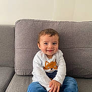 Aaron a rejoint le concours — aidez-le/la à gagner de superbes lots ! baby, blue_jeans, blue_socks, casual_clothing, child, couch, cozy, cute, fox_print, gray_couch, happy, home, indoor, person, portrait, sitting, smiling, toddler, white_shirt, young_child