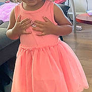 Veronica joined the competition — help win amazing prizes! child, girl, pink_dress, sandals, indoor, living_room, television, table, floor, hair, ponytails, smiling, furniture, wooden_floor, toy, curtains, casual_clothing, person, standing, home