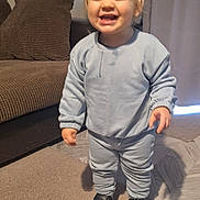 Frankie is registered to the contest to win money with this photo: toddler, child, smiling, pajamas, indoor, carpet, shoes, face, person, standing, living_room, couch, curtains, happy, home, clothing, infant, cute, young_child, portrait