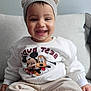 toddler, child, smiling, sweatshirt, hat, pom_poms, mickey_mouse, pluto, couch, beige_pants, happy, indoor, portrait, cute, clothing, face, baby, sitting, cozy, casual