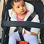 baby, child, stroller, toy, white_jacket, pink_clothing, hair_clips, curious, seated, outdoor, safety_harness, footwear, face, person, infant, cute, expression, warm_clothing, baby_accessory, pensive
