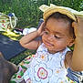 Malika a rejoint le concours — aidez-le/la à gagner de superbes lots ! baby, casual, child, cute, floral_dress, fun, grass, greenery, happy, hat, nature, outdoor, person, picnic, playful, sitting, smiling, summer, sunlight, toddler