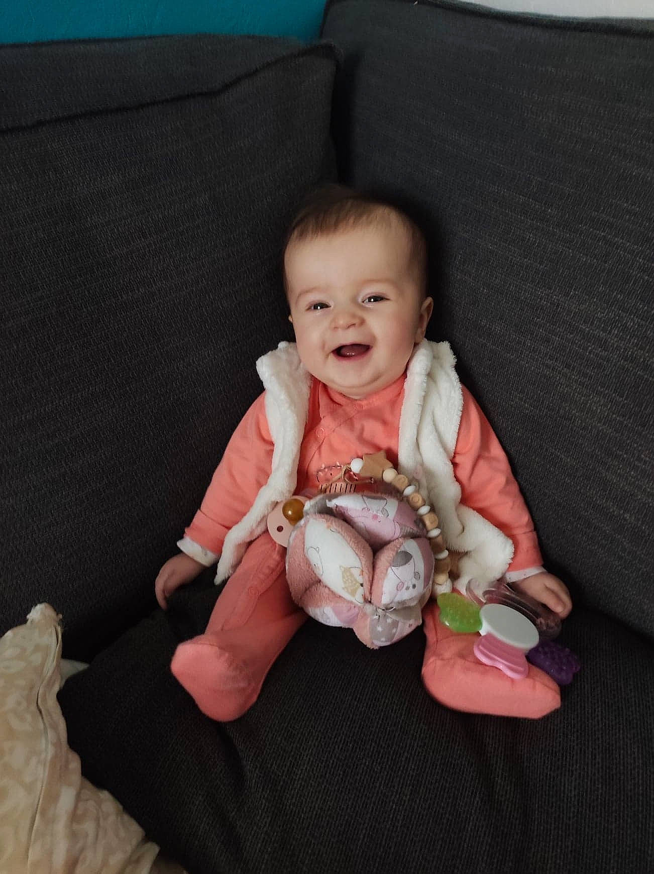 Lilou participe au concours pour gagner de l'argent avec cette photo : baby, baby_toddler_clothing, cheek, comfort, couch, dress, eye, face, finger, gesture, happy, head, human_body, lap, person, skin, sleeve, smile, textile, thumb