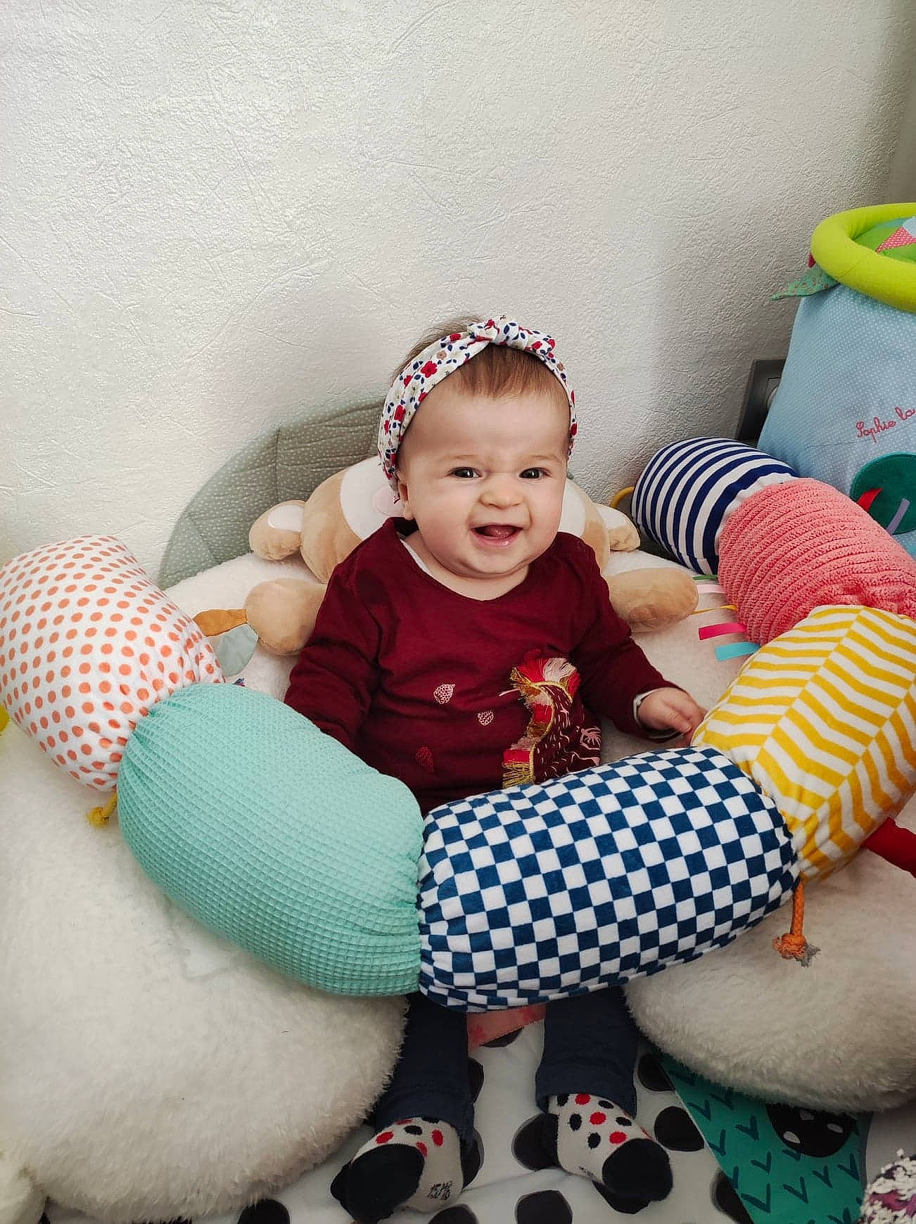 Lilou a rejoint le concours — aidez-le/la à gagner de superbes lots ! baby, baby_toddler_clothing, cap, comfort, eye, face, fun, happy, head, knee, lap, leg, person, pink, red, skin, smile, sock, textile, thigh
