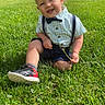 child, toddler, baby, smiling, outdoor, grass, lawn, forest, nature, portrait, bow_tie, suspenders, plaid_shirt, shorts, sneaker, sitting, sunlight, greenery, happy, outdoor_portrait