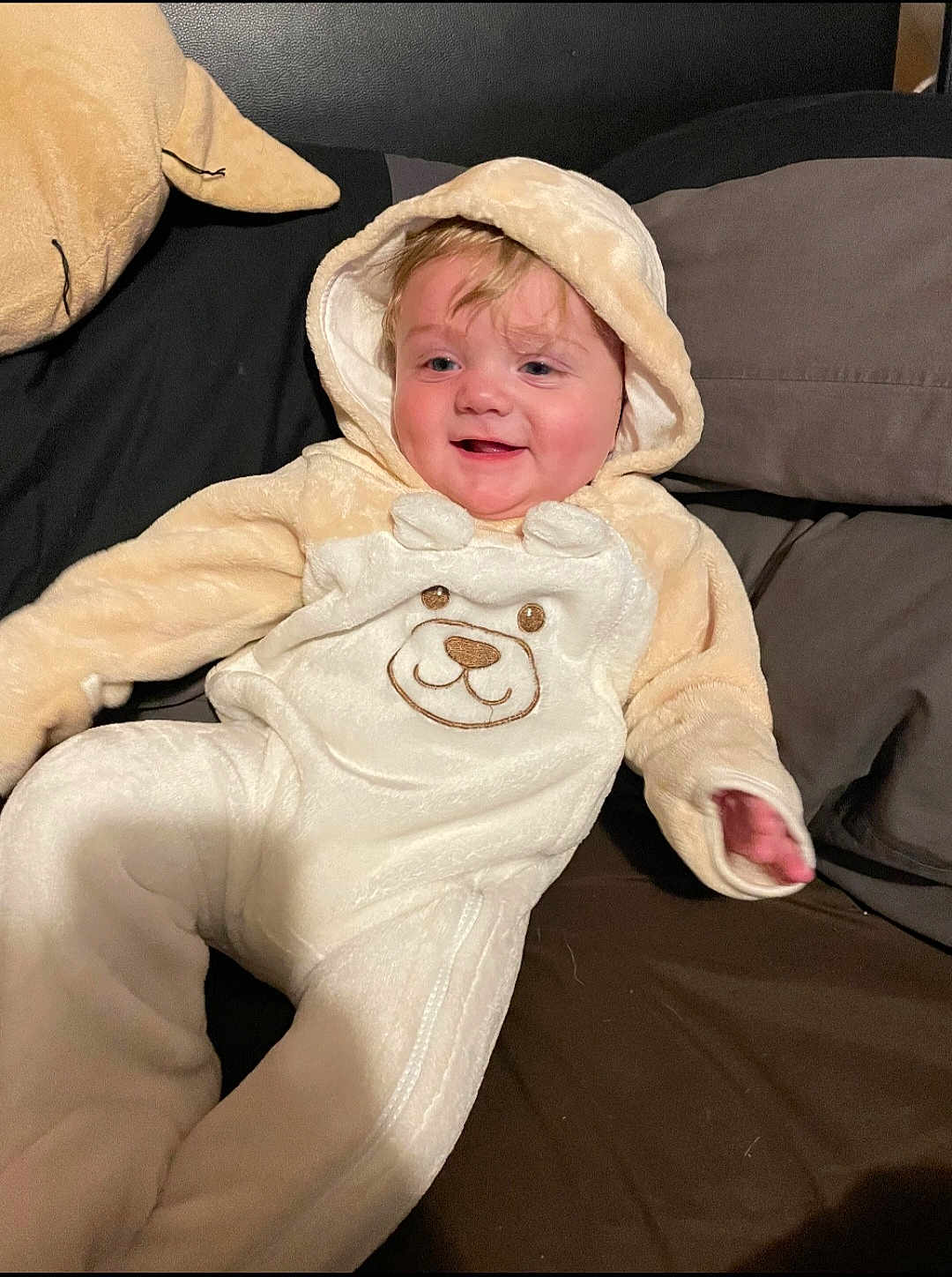Cyrus joined the competition — help win amazing prizes! baby, child, onesie, bear_design, hooded_clothing, couch, pillow, smile, happy, indoor, plush, cute, infant, soft_fabric, relaxing, portrait, person, face, cozy, seated