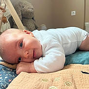 Mila participe au concours pour gagner de l'argent avec cette photo : baby, infant, quilt, plush_toy, bunny, play_gym, floor, child, cute, soft_lighting, indoors, lying_down, white_clothing, pink_socks, nursery, toy, smile, face, head, hand