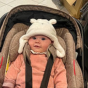 Aimée participe au concours pour gagner de l'argent avec cette photo : baby, bear_ears, black_straps, car_seat, cardboard_box, child, cute, hat, headwear, indoors, infant, person, pink_clothing, seat_belt, sitting, smile, soft_fabric, tiled_floor, white_hat, young_child