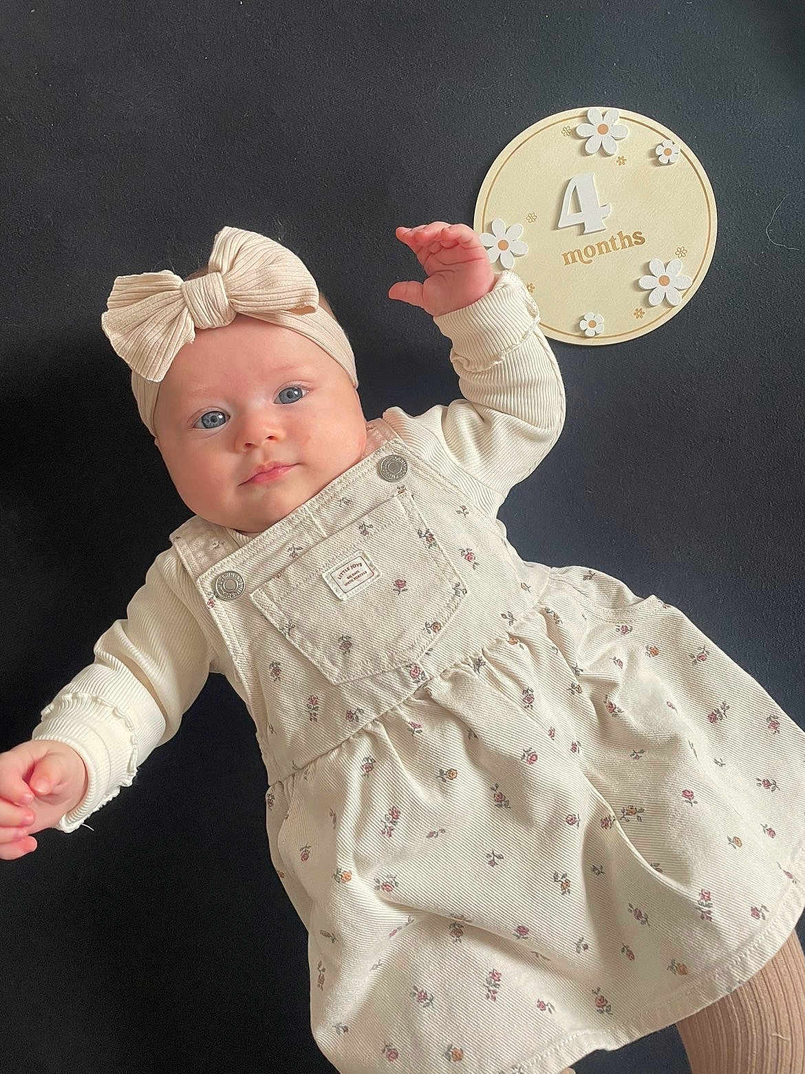 Aimée participe au concours pour gagner de l'argent avec cette photo : baby, child, infant, blue_eyes, bow, headband, cream_color, dress, floral_pattern, milestone, age_sign, 4_months, hand, lying_down, cute, portrait, face, skin, clothing, indoor