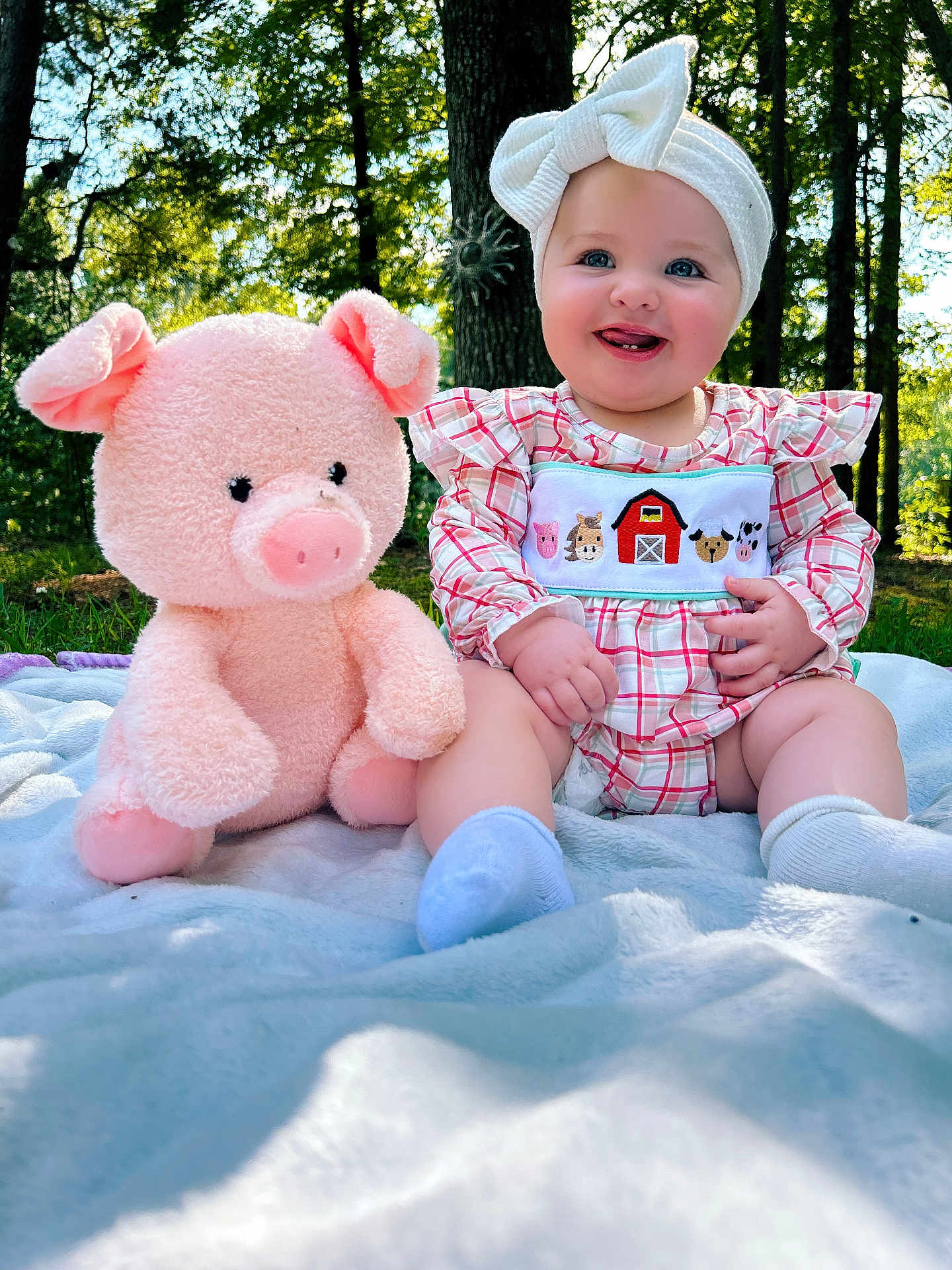 Aria joined the competition — help win amazing prizes! baby, child, smiling, outdoor, plush_toy, stuffed_animal, blanket, headband, bow, trees, grass, sunlight, happy, cute, infant, nature, sitting, clothing, portrait, playful