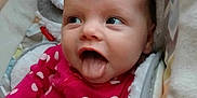 Paisley joined the competition — help win amazing prizes! baby, infant, tongue_out, polka_dot, pink_clothing, blanket, cozy, cute, face, expression, child, cute_baby, soft_texture, indoors, person, closeup, smiling, happy, playful, resting