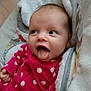 baby, infant, tongue_out, polka_dot, pink_clothing, blanket, cozy, cute, face, expression, child, cute_baby, soft_texture, indoors, person, closeup, smiling, happy, playful, resting