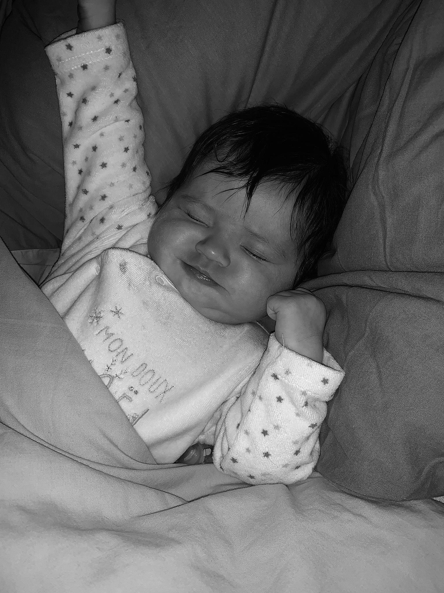Selena participe au concours pour gagner de l'argent avec cette photo : arm, baby, baby_sleeping, bedding, bedtime, child, comfort, elbow, finger, gesture, hand, linens, mammal, monochrome, monochrome_photography, mouth, person, room, sitting, textile