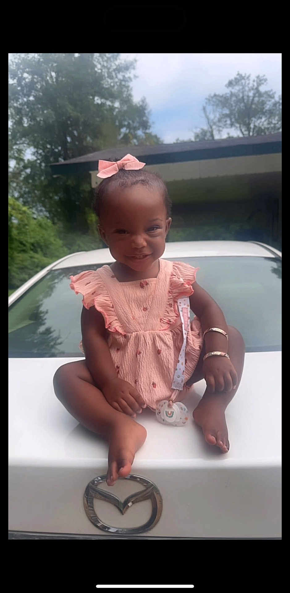 Ko'Hana is registered to the contest to win money with this photo: toddler, child, smiling, pink_dress, bow, car, mazda, pacifier, bracelet, outdoor, hood, white_car, greenery, house, sky, cute, sitting, happy, portrait, baby