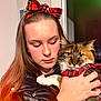 Annabelle joined the competition — help win amazing prizes! woman, cat, pet, plaid, red_bow, red_plaid, long_hair, leather_jacket, indoor, affection, close_up, portrait, holding, cozy, cute, feline, warm_lighting, human, animal, soft_expression