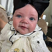 Ivy-Mae is registered to the contest to win money with this photo: baby, child, face, headband, bow, blue_eyes, white_outfit, stars, couch, indoor, portrait, cute, infant, smile, clothing, person, young_child, happy, soft_light, closeup