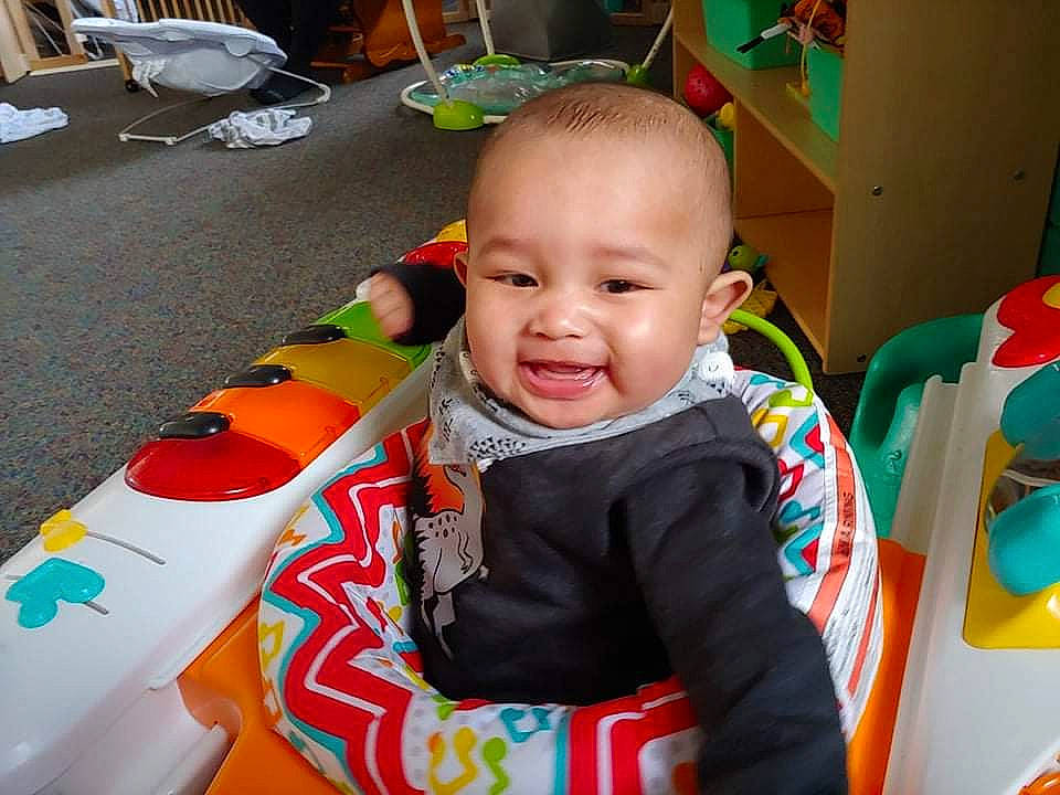 Lamar is registered to the contest to win money with this photo: baby, baby_playing_with_toys, baby_products, baby_toddler_clothing, baby_toys, child, event, face, fun, green, happy, joy, leisure, person, play, recreation, room, sharing, sitting, smile