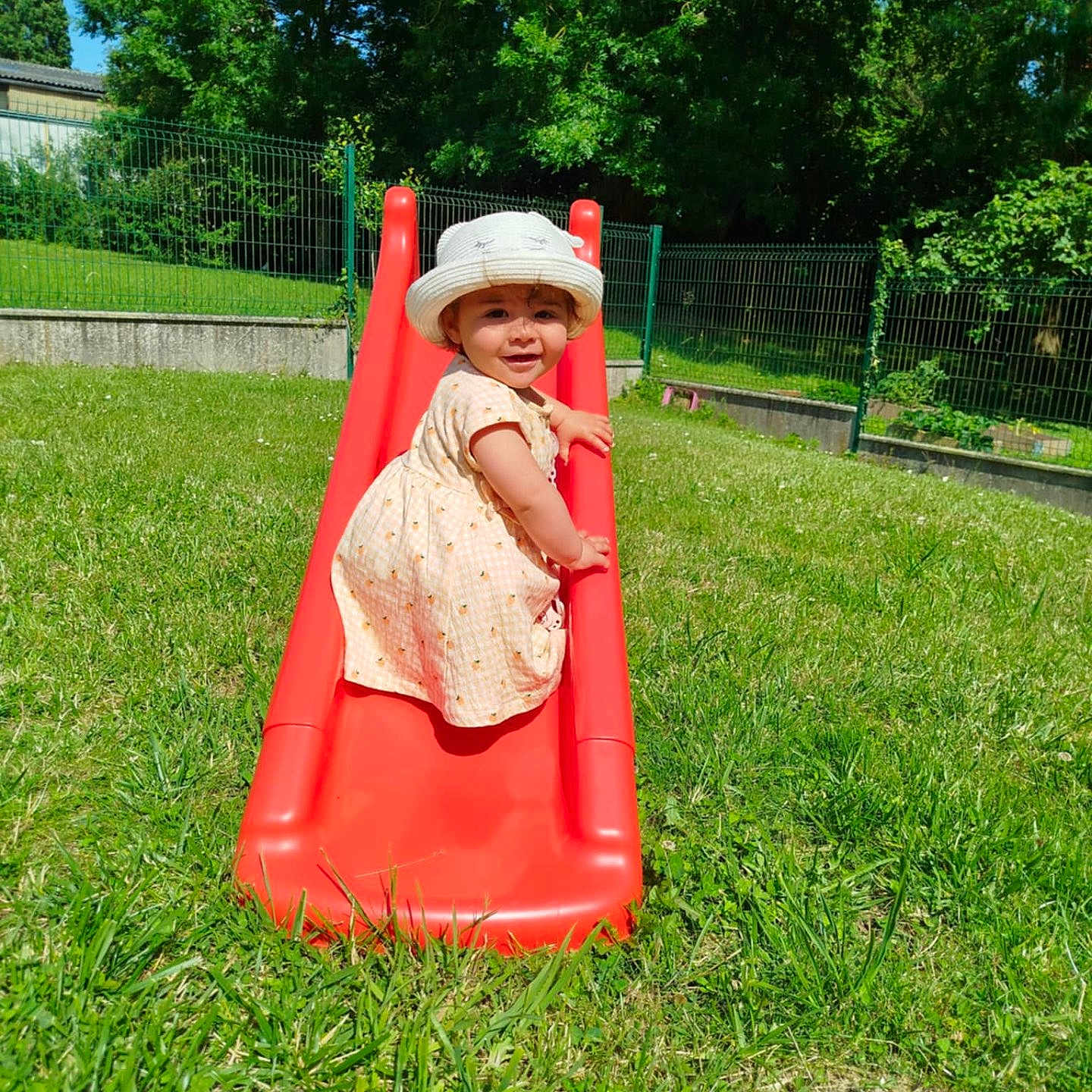 Romy participe au concours pour gagner de l'argent avec cette photo : child, climbing, daylight, dress, fence, fun, grass, greenery, happy, hat, outdoor, park, person, play, playground, slide, smile, summer, sunny, toddler