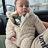 adult_arm, baby, car_door, car_interior, casual, child, curious, fluffy_clothing, green_shirt, indoor, infant, onesie, person, portrait, rain, raindrops, seat, warm_clothing, weather, window
