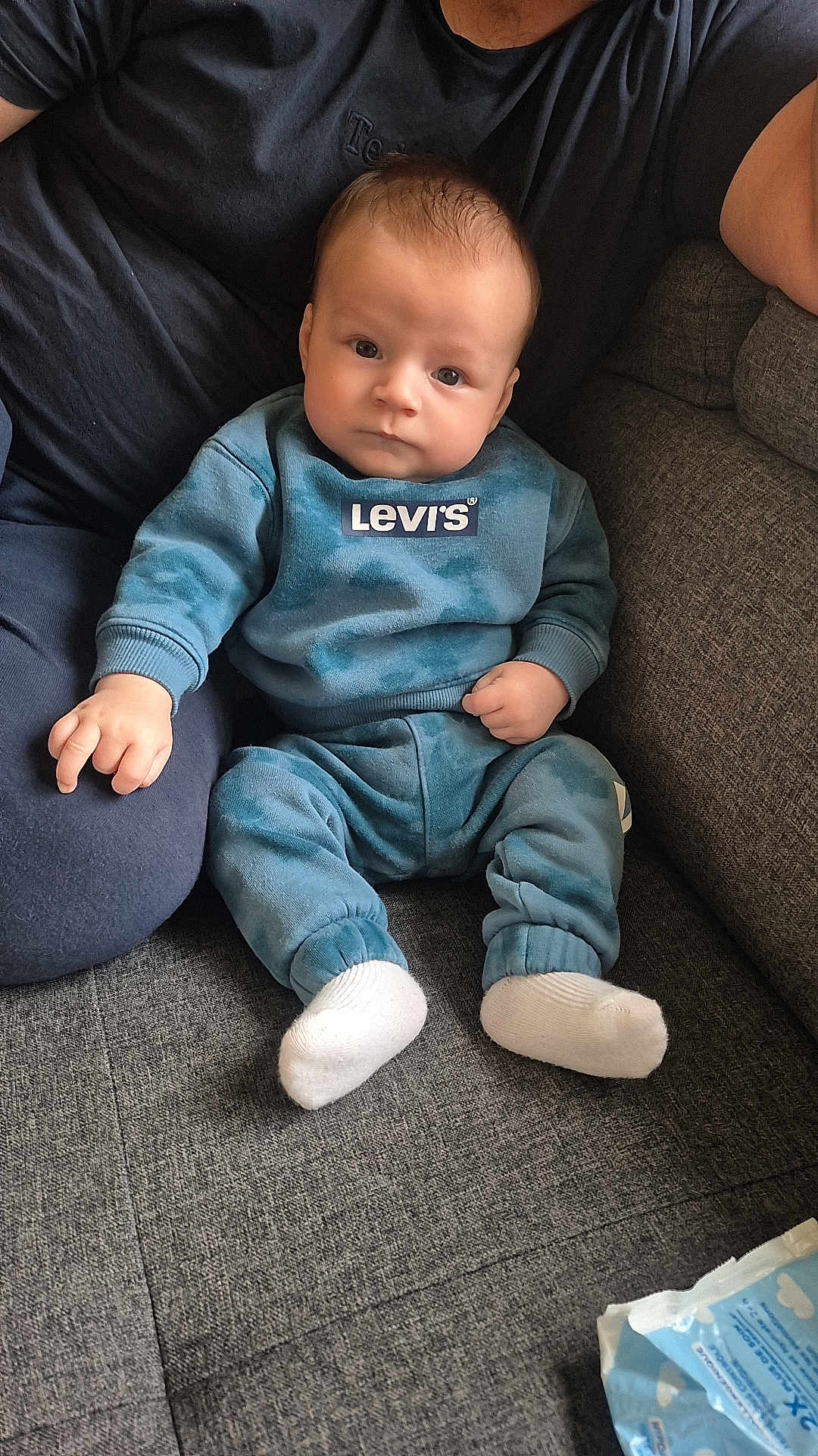 ésaïe participe au concours pour gagner de l'argent avec cette photo : baby, infant, child, person, couch, sofa, clothing, blue, levis, socks, adult, hand, face, head, indoor, seated, soft_fabric, wipes, curious, casual