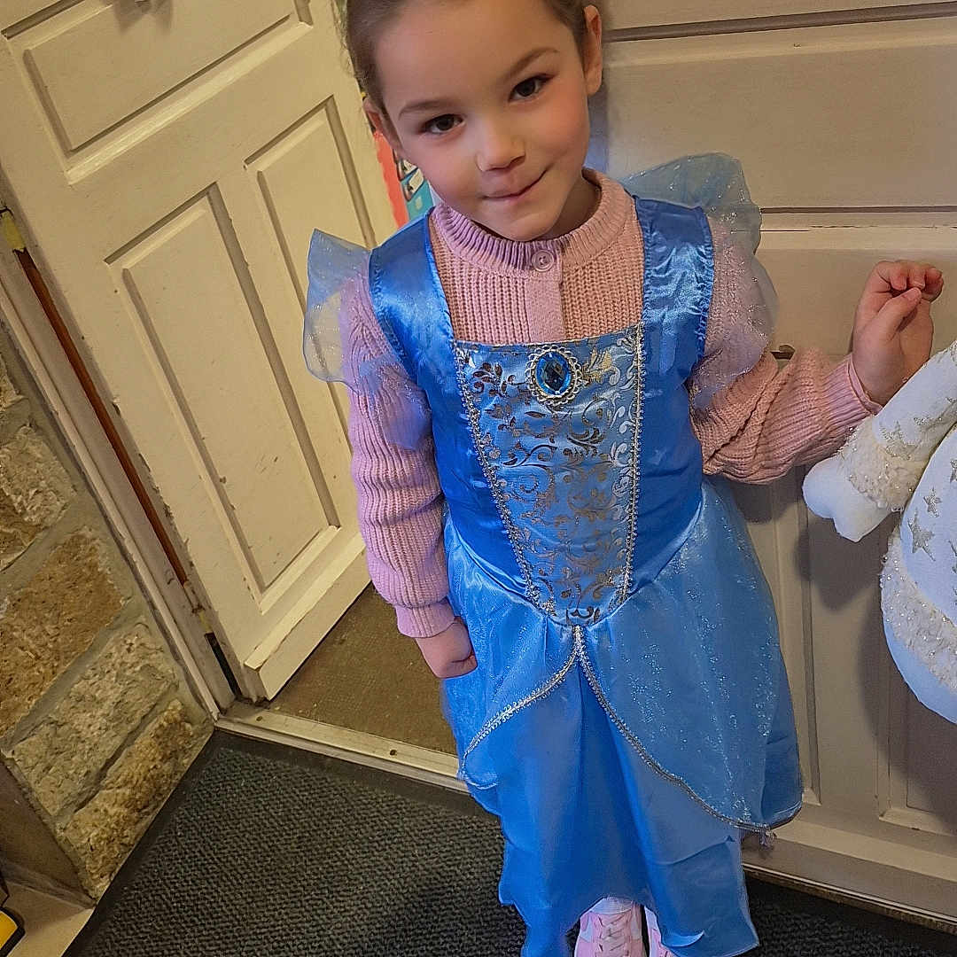 Maïana participe au concours pour gagner de l'argent avec cette photo : blue_dress, carpet, child, costume, cute, door, girl, headband, indoor, pink_shoes, pink_sweater, playful, portrait, princess_dress, shoes, smiling, standing, stone_wall, wall, young