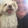 Bella is registered to the contest to win money with this photo: dog, person, smile, indoor, happy, animal, pet, curly_fur, tongue_out, face, hand, necklace, cross, closeup, friendship, cute, portrait, companion, human, light