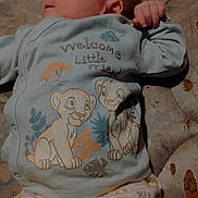 Bradley is registered to the contest to win money with this photo: baby, infant, pajamas, cartoon_characters, lion, sleepwear, child, cute, lying_down, mattress, fabric, clothing, hand, face, skin, newborn, bedroom, soft_colors, pattern, gaze