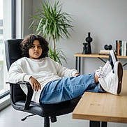 Petro joined the competition — help win amazing prizes! black_chair, casual, child, contemplative, curly_hair, desk, furniture, indoor, jeans, minimalist, modern, office_chair, person, plant, relaxed, seated, sneakers, white_sweater, window, wooden_desk
