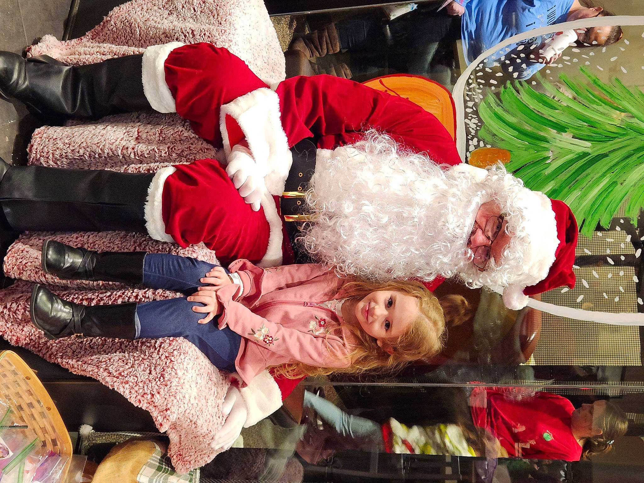 Mackenzie is registered to the contest to win money with this photo: christmas, christmas_decoration, christmas_eve, costume, event, fictional_character, fun, fur, green, happy, headwear, holiday, human_leg, joy, lap, leisure, pattern, person, santa_claus, smile