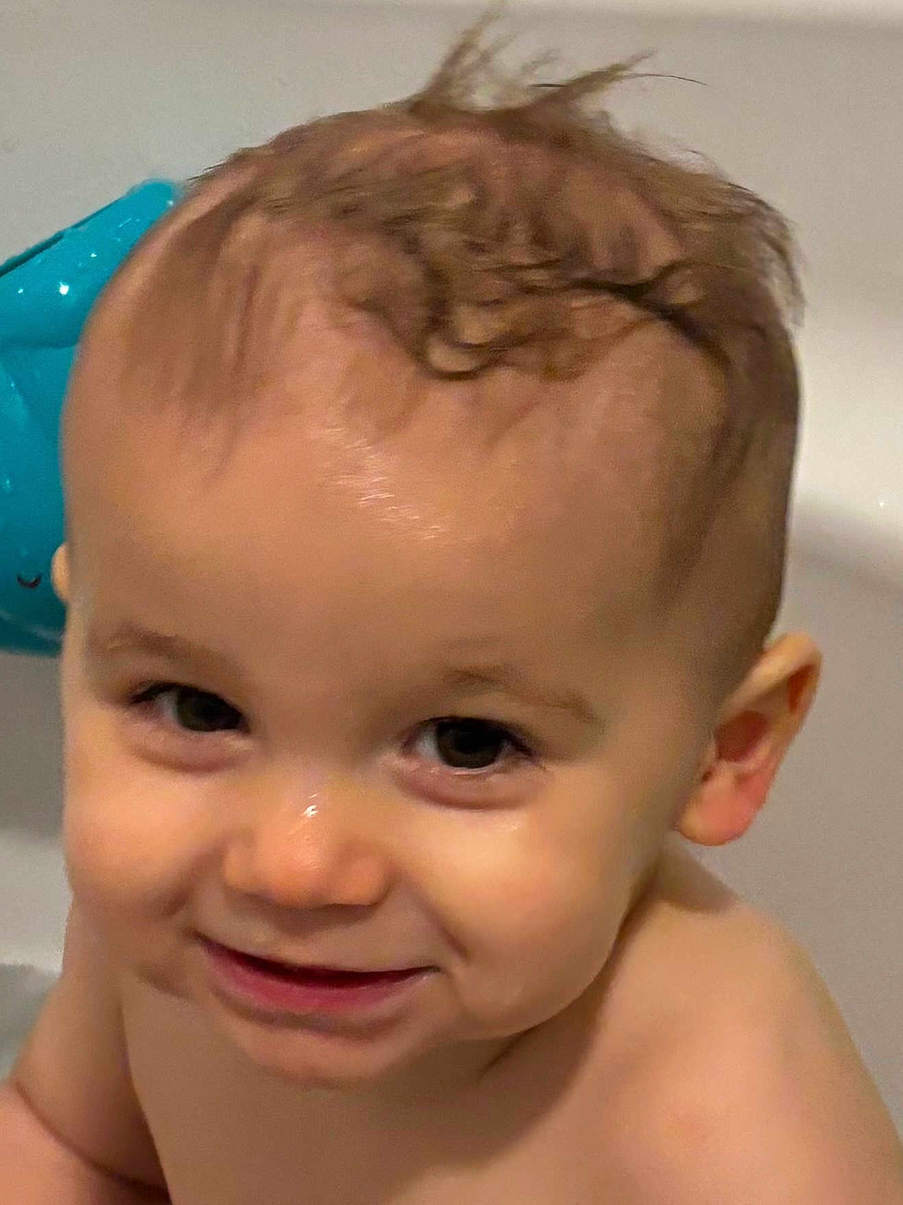Mathéo participe au concours pour gagner de l'argent avec cette photo : baby, infant, toddler, bath, bathtub, wet_skin, close_up, smile, eyes, curly_hair, face, cheek, ear, nose, mouth, toy, blue_plastic, water_droplet, portrait, happy_expression
