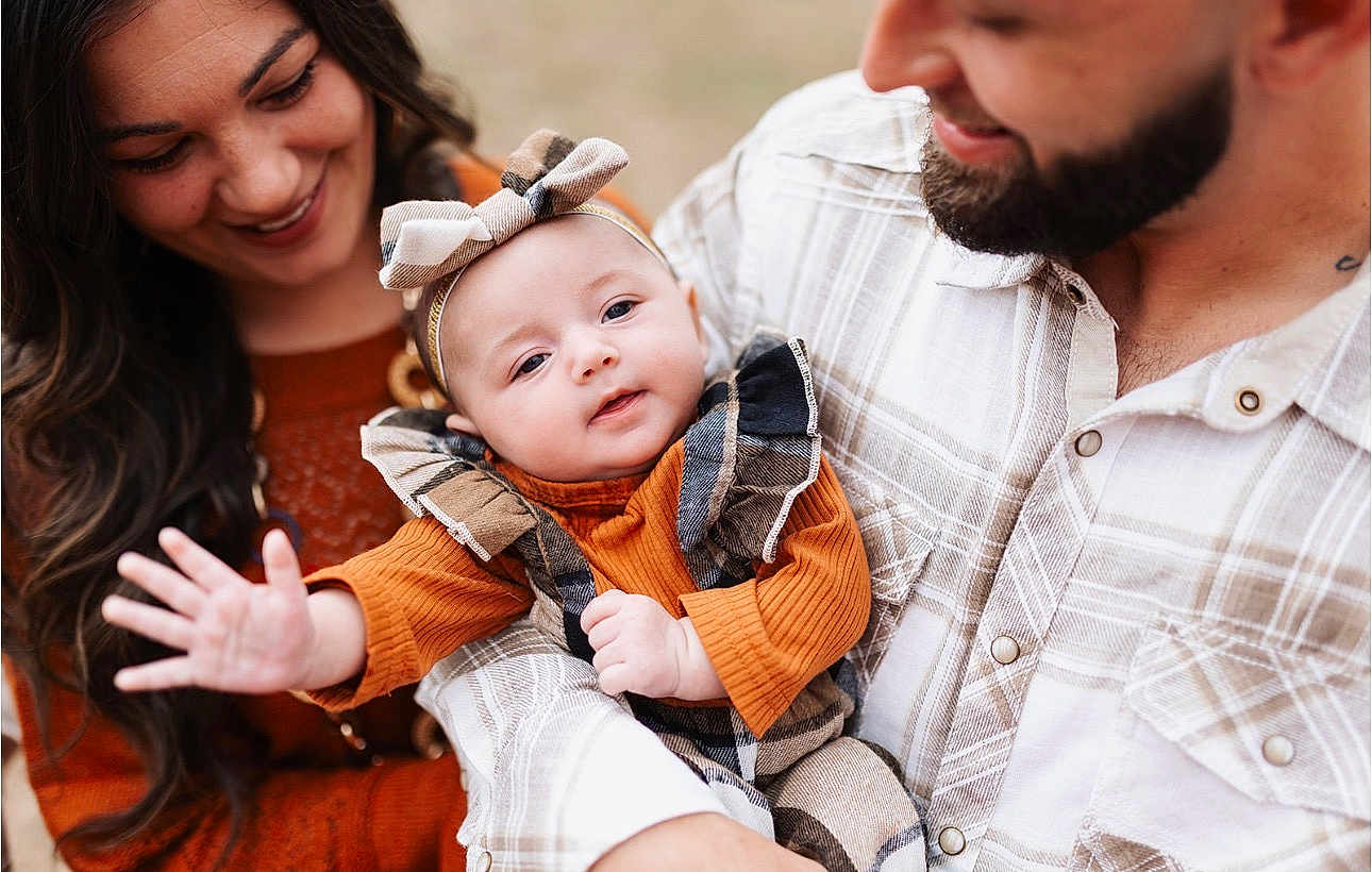 Harlynn is registered to the contest to win money with this photo: baby, child, woman, man, family, smile, love, outdoor, portrait, headband, plaid, clothing, beard, holding, happy, cute, toddler, parent, warm_colors, interaction