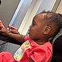 Jhazire is registered to the contest to win money with this photo: child, toddler, indoor, person, adult, interaction, table, coral_clothing, curly_hair, side_profile, reaching, casual, young_child, human, furniture, skin, face, hand, sitting, closeup
