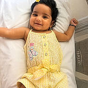 Vamika joined the competition — help win amazing prizes! baby, child, smiling, yellow_outfit, butterfly_patch, hair_clip, cushion, face, cute, infant, happy, indoors, lying_down, arm_up, bracelet, black_hair, portrait, soft_lighting, baby_clothes, white_background
