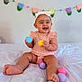 Aleia joined the competition — help win amazing prizes! baby, child, infant, smiling, headband, pink_clothing, plastic_eggs, bed, white_bedspread, tulip_garland, decorations, happy, indoors, cute, sitting, playful, chubby_legs, pastel_colors, celebration, portrait
