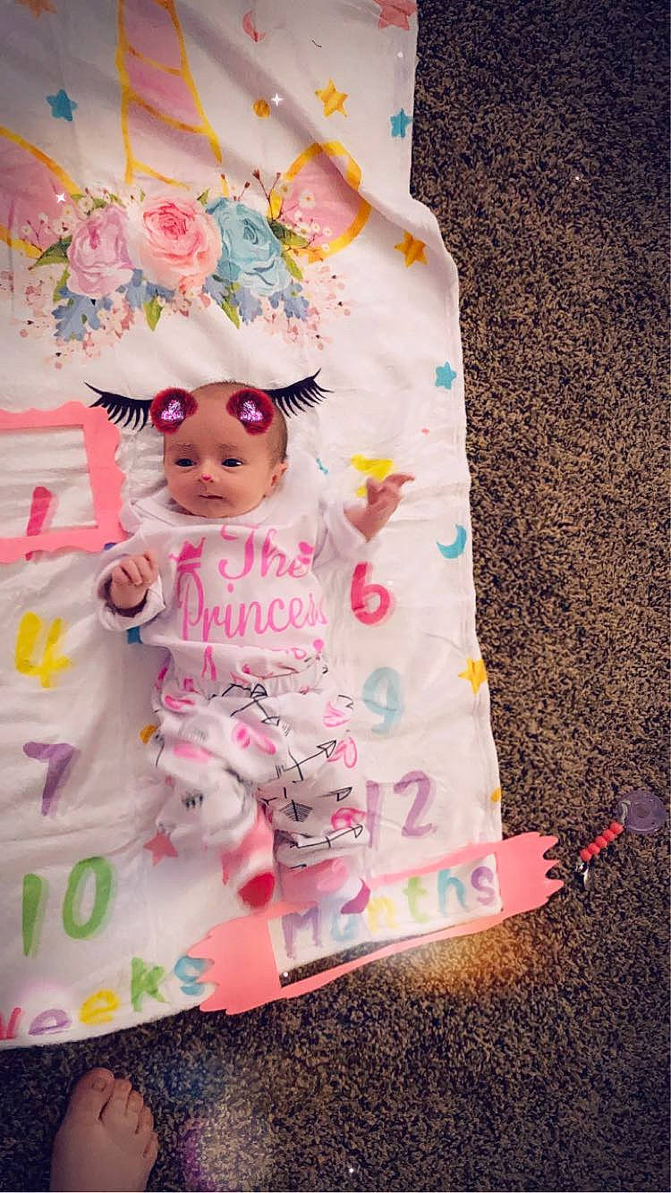 Arieanna is registered to the contest to win money with this photo: baby, baby_toddler_clothing, child, dress, embellishment, fashion_accessory, font, happy, linens, magenta, pattern, peach, person, petal, pink, sleeve, sock, t_shirt, textile, toddler